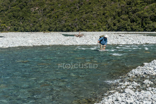 Hombre cruzando río - foto de stock