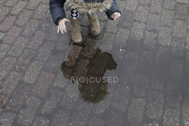 Девушка смотрит на отражение в луже — стоковое фото