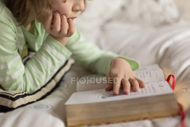 Мальчик лежит на кровати и читает — стоковое фото