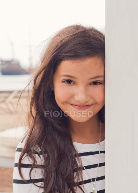 Chica en vestido a rayas sonriendo en la playa - foto de stock