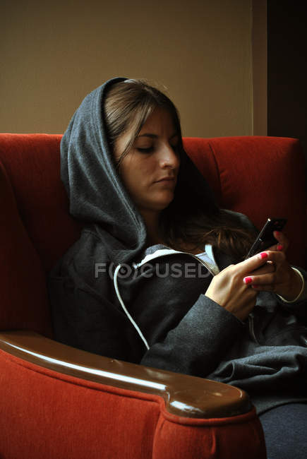 Mulher usando telefone sentado no sofá — Fotografia de Stock