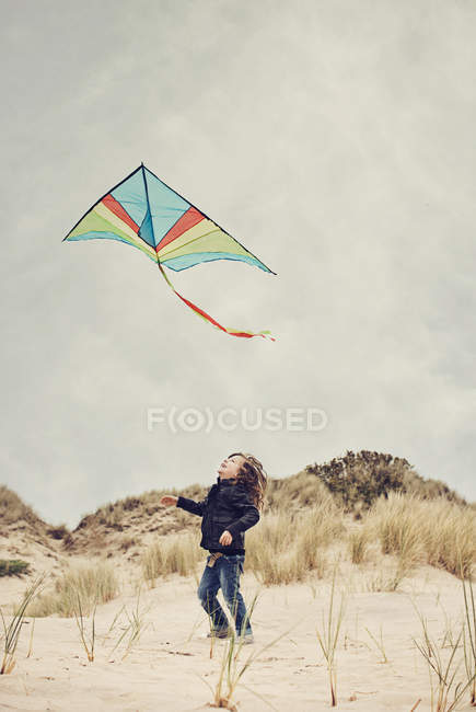 Мальчик запускает воздушного змея на пляже — стоковое фото