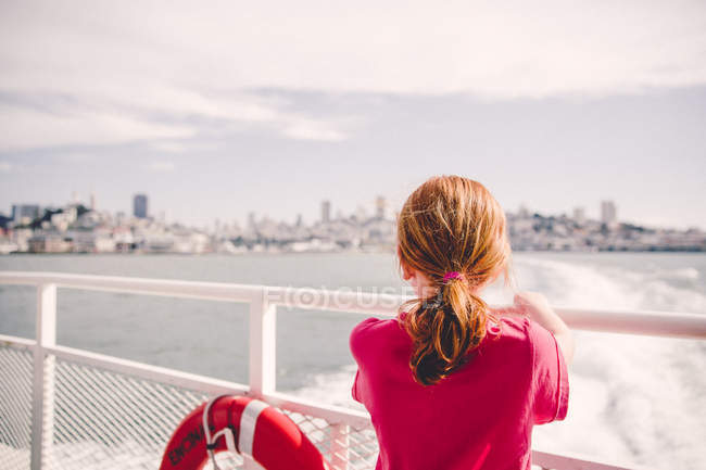 Menina em ferry olhando para o horizonte da cidade — Fotografia de Stock