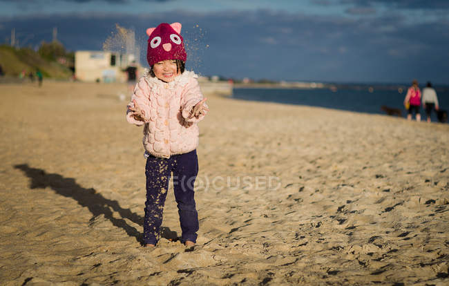 Chica jugando en la playa de arena - foto de stock