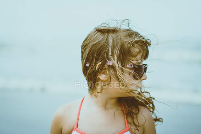 Fille aux cheveux blonds balayés par le vent portant des lunettes de soleil — Photo de stock