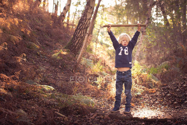 Хлопчик з палицею в лісі — стокове фото