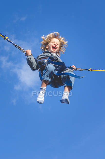 Sonriente chico en bungee swing - foto de stock