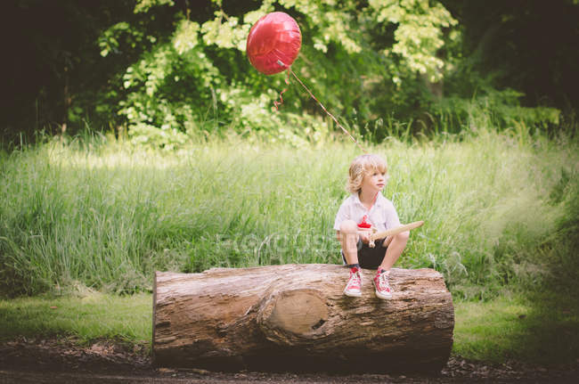 Giovane ragazzo seduto sul tronco — Foto stock