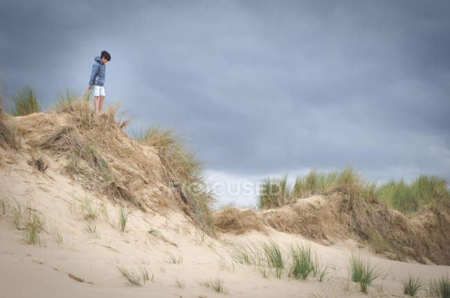 Мальчик стоит на травянистых дюнах — стоковое фото