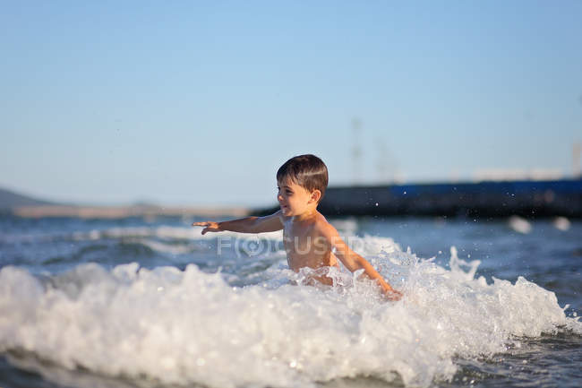 Garçon marchant dans les vagues de mer — Photo de stock