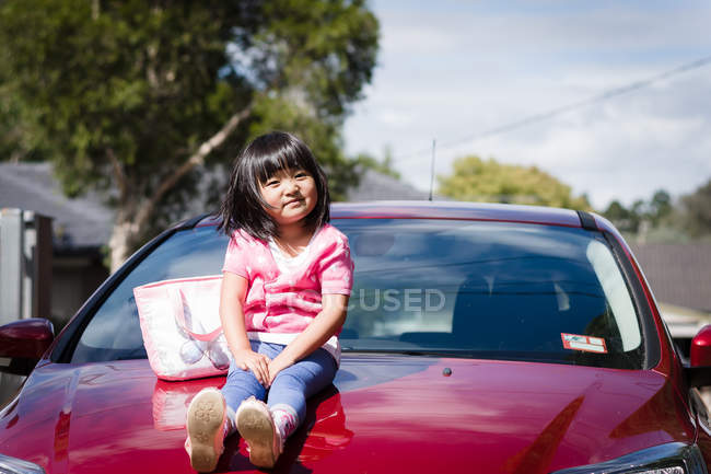 Petite fille sur voiture rouge — Photo de stock