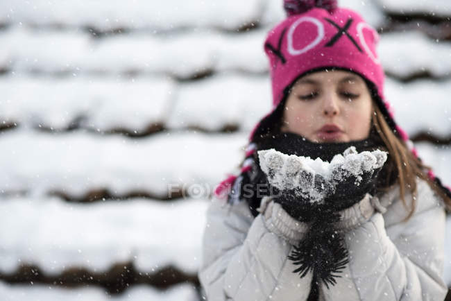 Mädchen bläst eine Handvoll Schnee — Stockfoto