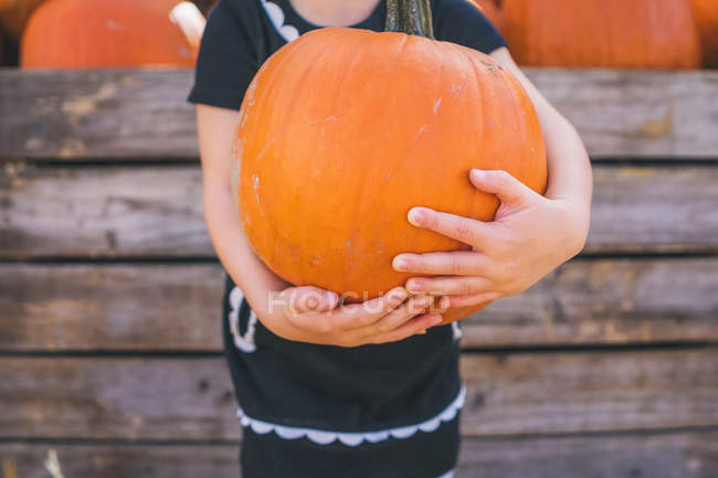 Girl holding large pumpkin — Stock Photo