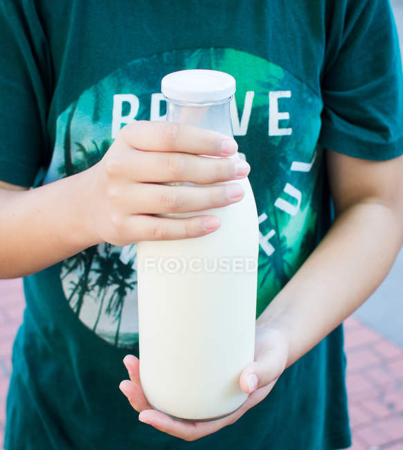Хлопчик тримає в руках пляшку молока — стокове фото