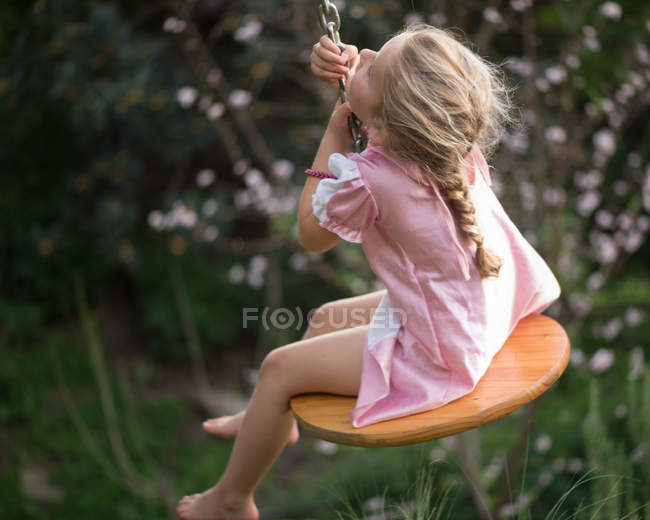 Jeune fille assise sur swing — Photo de stock