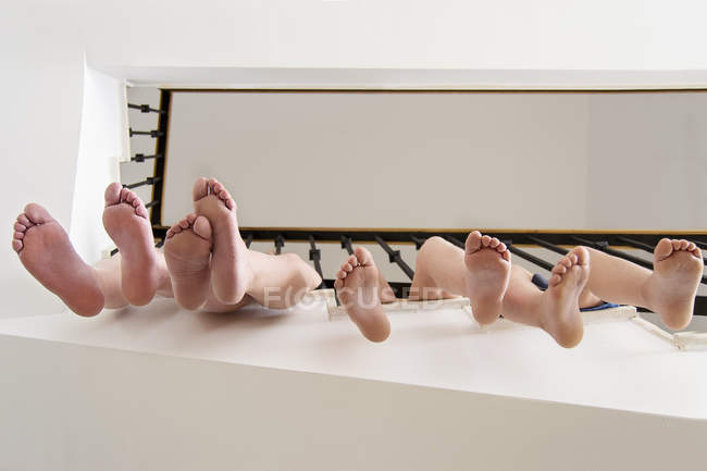 Children legs hanging through railings — Stock Photo