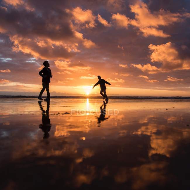 Niños pequeños caminando sobre el agua en la playa - foto de stock