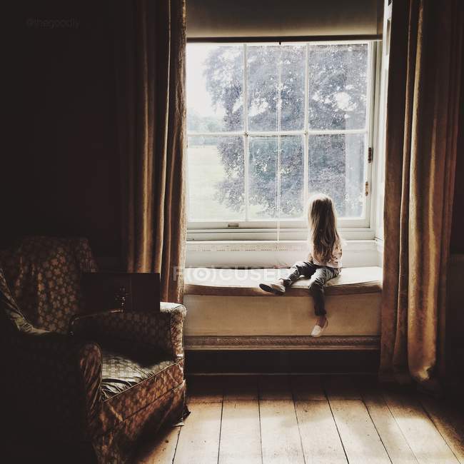 Petite fille regardant par la fenêtre — Photo de stock