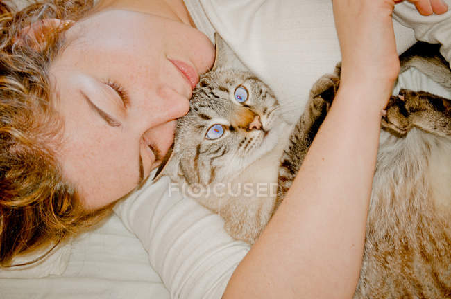 Женщина обнимает кота в постели — стоковое фото