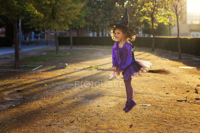 Chica jugando volando en escoba - foto de stock