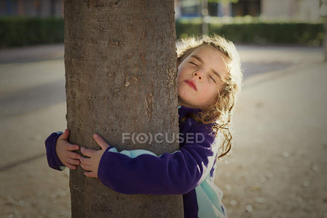 Menina abraçando tronco árvore — Fotografia de Stock