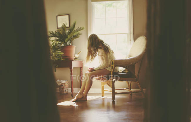 Young woman sitting in living room — Stock Photo