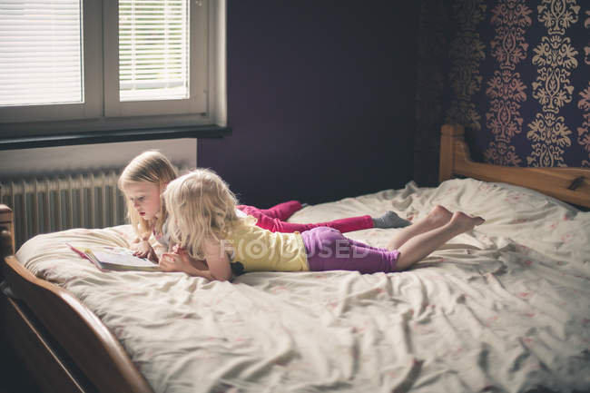 Two girls lying on bed — Stock Photo