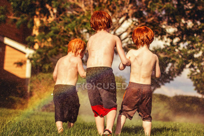 Hermanos jugando en aspersores - foto de stock