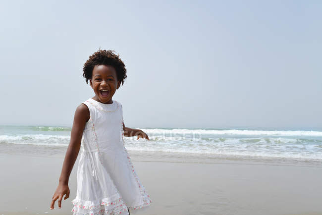 Mädchen steht am Strand und lacht in die Kamera — Stockfoto