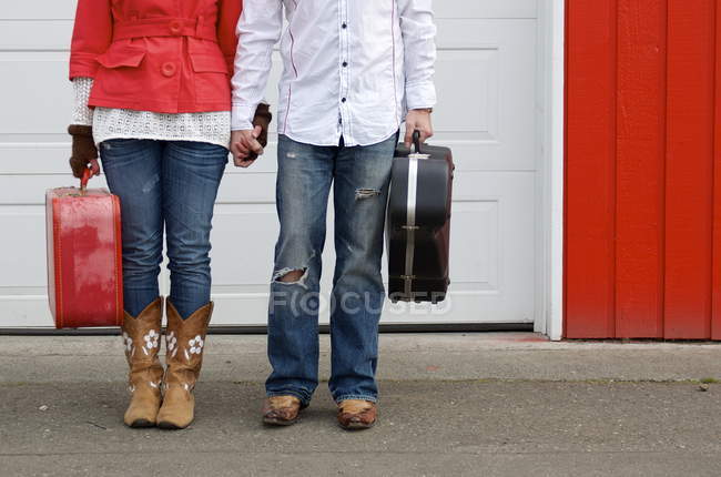 Couple holding hands with cases — Stock Photo