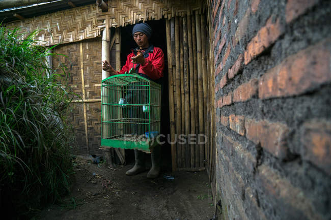 Homme tenggérien tenant une cage à oiseaux — Photo de stock