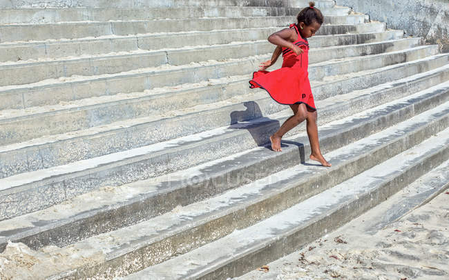 Menina de vestido correndo para baixo passos — Fotografia de Stock
