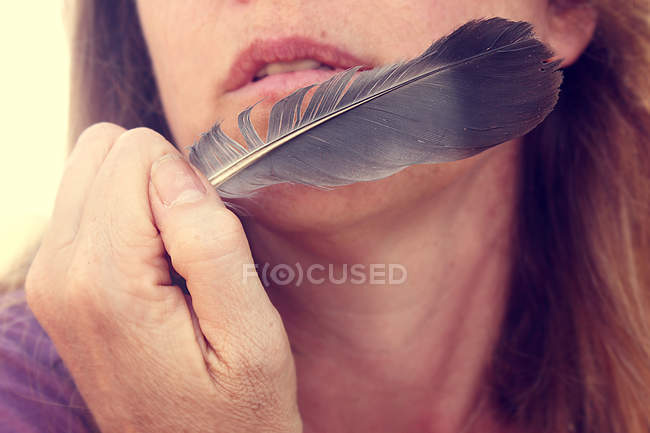 Femme tenant plume près du visage — Photo de stock