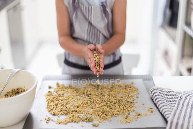 Girl making crumble over baking tray — Stock Photo