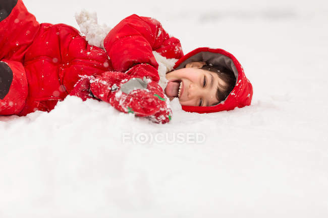 Menino deitado na neve — Fotografia de Stock