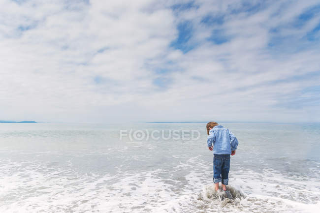 Garçon debout sur le rocher dans la mer — Photo de stock