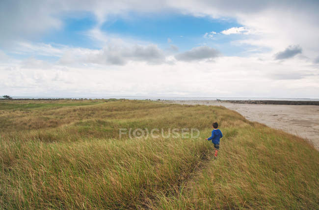 Garçon courir à travers l'herbe — Photo de stock