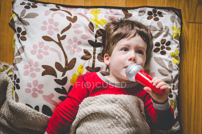 Ragazzo sul pavimento che canta in microfono giocattolo — Foto stock