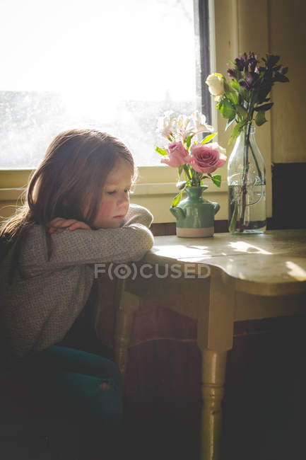 Девушка сидит за кухонным столом — стоковое фото