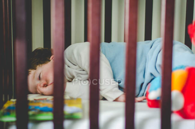 Junge schläft im Kinderbett — Stockfoto
