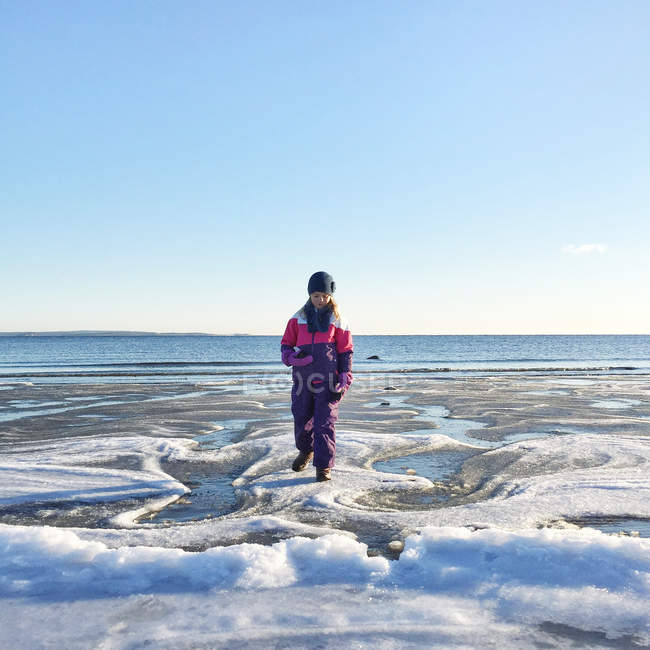Girl walking on icy beach — Stock Photo