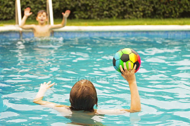 Мальчики играют в мяч в бассейне — стоковое фото