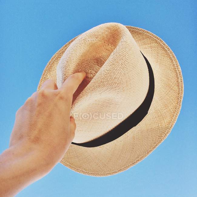 Hand holding hat up to sky — Stock Photo