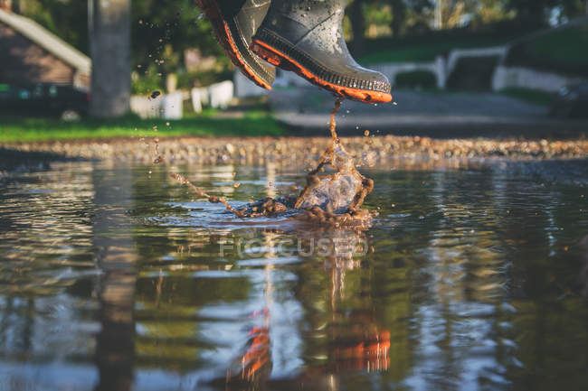 Garçon sautant dans la flaque boueuse — Photo de stock