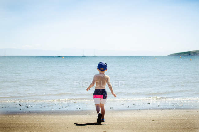 Хлопчик на пляжі біжить до моря — стокове фото