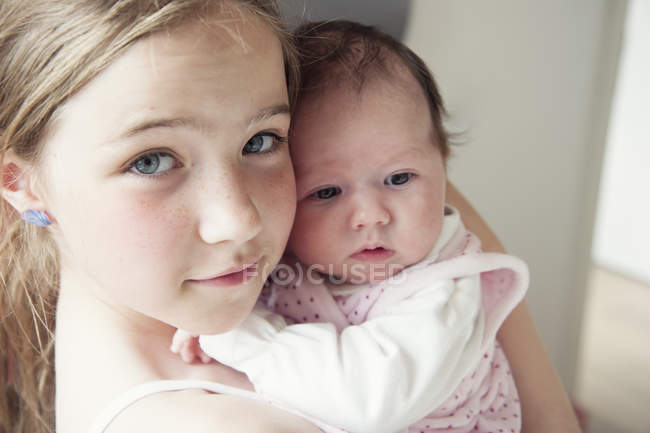 Girl holding her newborn baby sister — Stock Photo