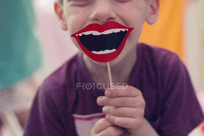 Boy holding smile prop on stick — Stock Photo