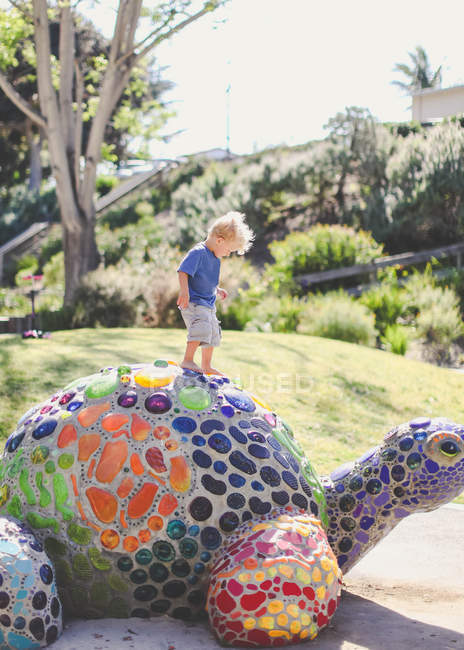 Boy standing on a mosaic turtle — Stock Photo