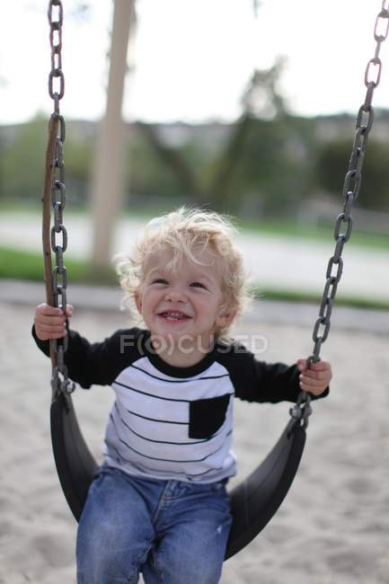 Garçon souriant sur swing — Photo de stock