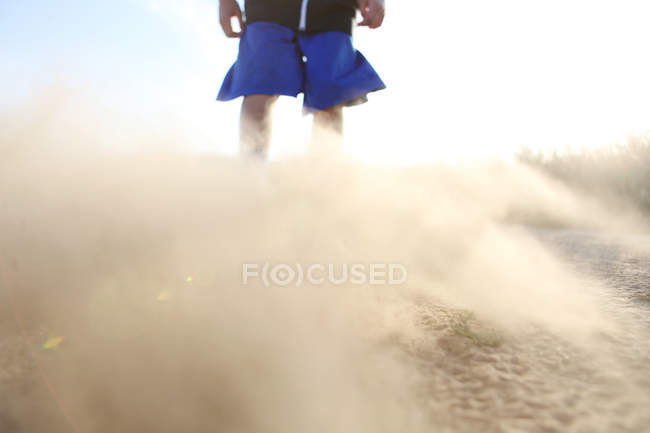 Garçon en short avec sable soufflant — Photo de stock